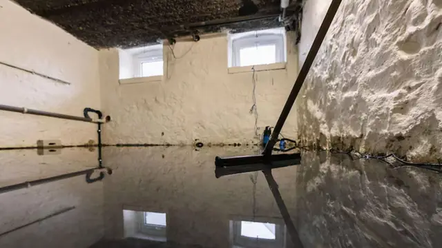 Standing water on a basement floor with a squeegee at the edge